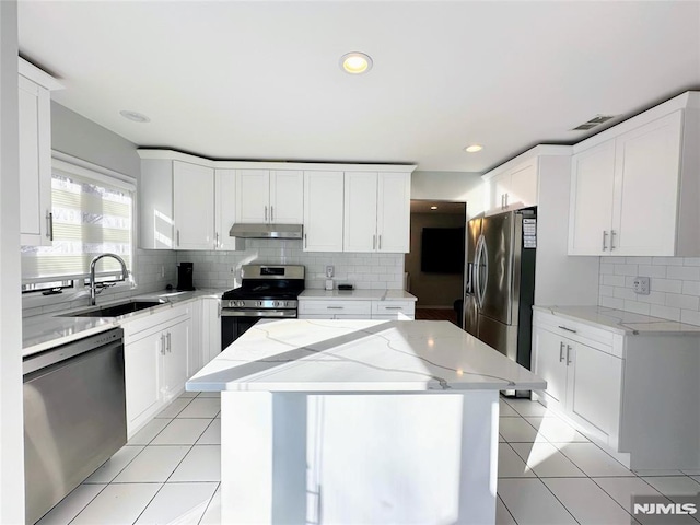 kitchen with appliances with stainless steel finishes, sink, white cabinetry, and a center island