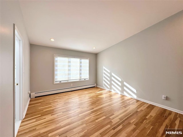 spare room with a baseboard heating unit and light hardwood / wood-style floors