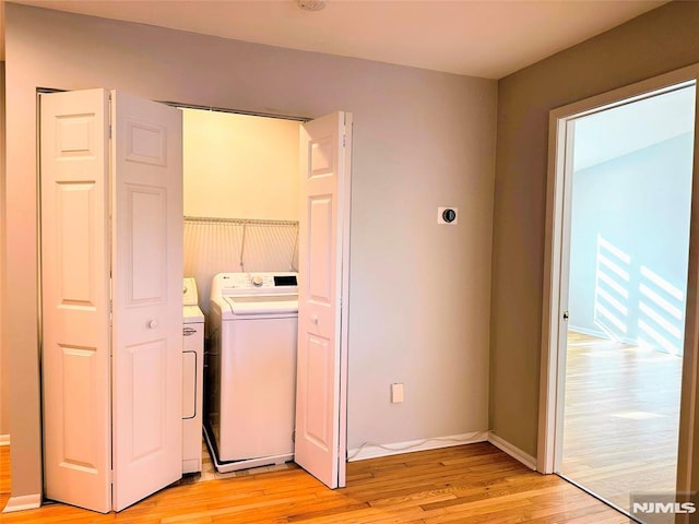 laundry area with washer and dryer and light hardwood / wood-style flooring