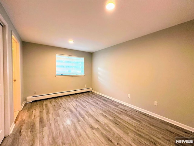 unfurnished bedroom featuring a baseboard heating unit and light hardwood / wood-style flooring