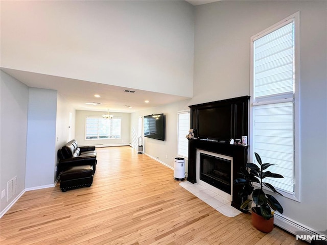 living room with a baseboard heating unit, a chandelier, and light hardwood / wood-style floors