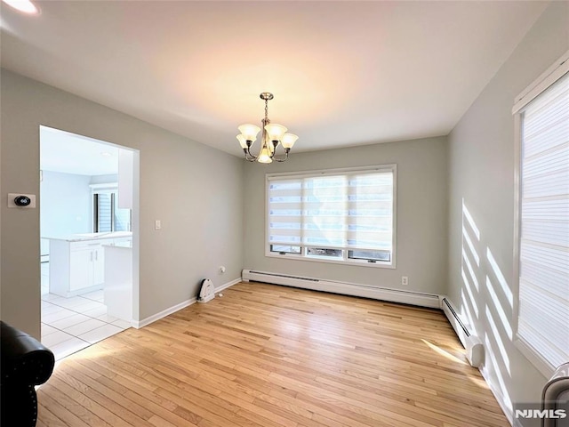 empty room with light wood-type flooring, a chandelier, and a baseboard radiator