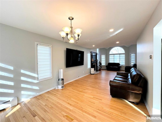 living room with baseboard heating, a chandelier, and light hardwood / wood-style floors