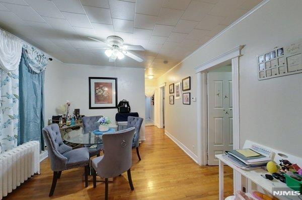 dining room featuring ceiling fan, radiator, and light wood-type flooring