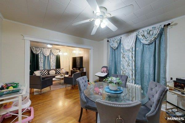 dining space with wood-type flooring, ceiling fan, and crown molding