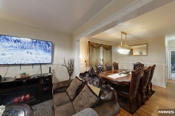 dining space with hardwood / wood-style floors, ornamental molding, and a notable chandelier