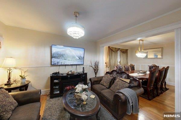 living room with wood-type flooring, crown molding, and a chandelier