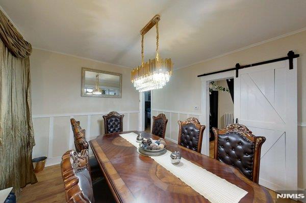 dining area with a notable chandelier, hardwood / wood-style flooring, and a barn door