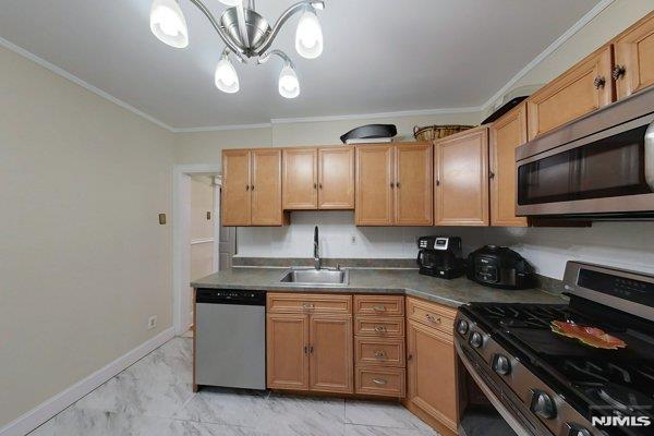 kitchen with decorative light fixtures, sink, appliances with stainless steel finishes, and crown molding