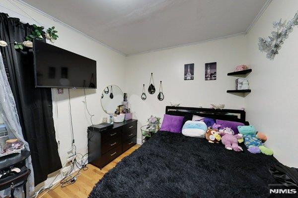 bedroom with light hardwood / wood-style flooring and crown molding