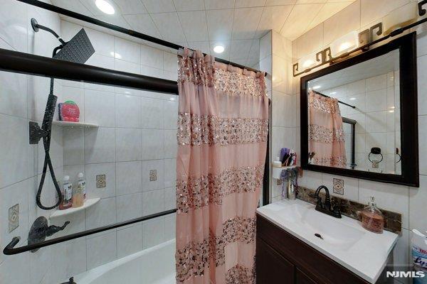 bathroom with vanity, tile walls, and shower / bath combo