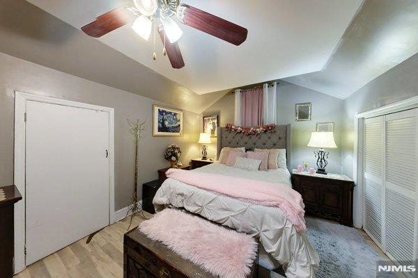 bedroom with ceiling fan, light hardwood / wood-style floors, a closet, and vaulted ceiling