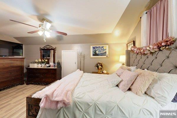 bedroom featuring ceiling fan, light hardwood / wood-style flooring, and lofted ceiling