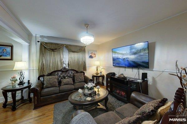 living room with hardwood / wood-style flooring, crown molding, and a fireplace