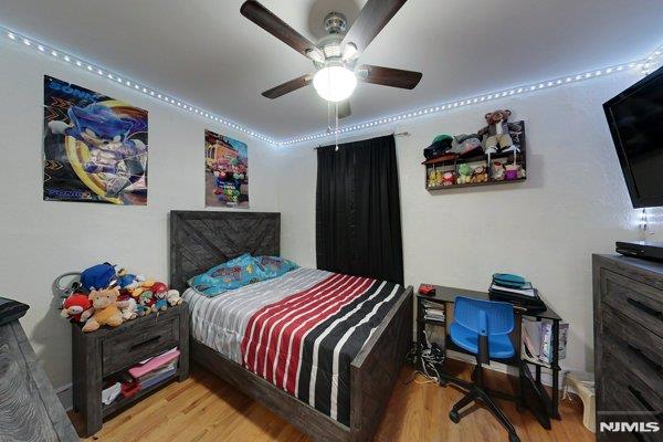 bedroom with wood-type flooring, ceiling fan, and crown molding