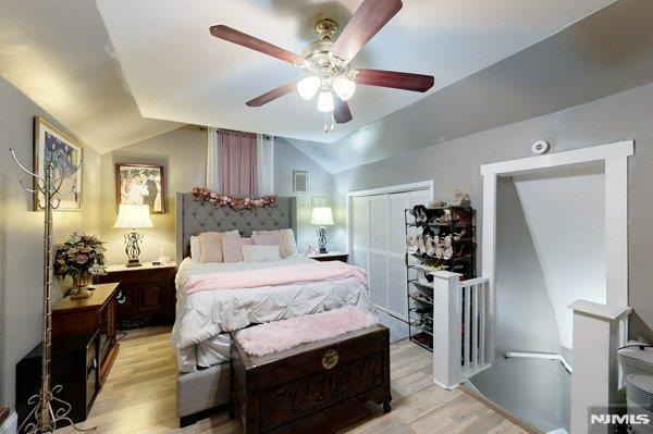 bedroom with lofted ceiling, light hardwood / wood-style floors, a closet, and ceiling fan