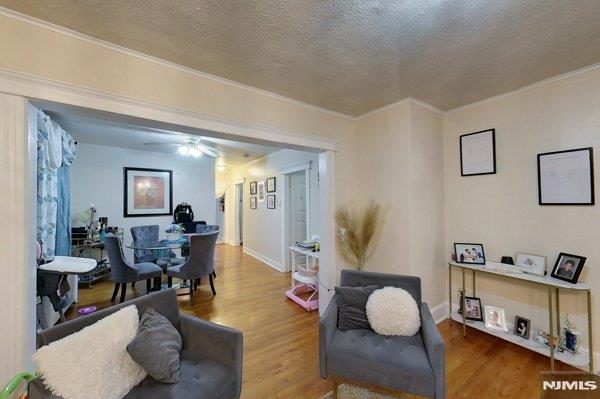 home office with hardwood / wood-style flooring, a textured ceiling, ceiling fan, and ornamental molding