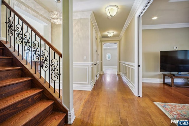 entryway featuring crown molding, a chandelier, and light hardwood / wood-style floors