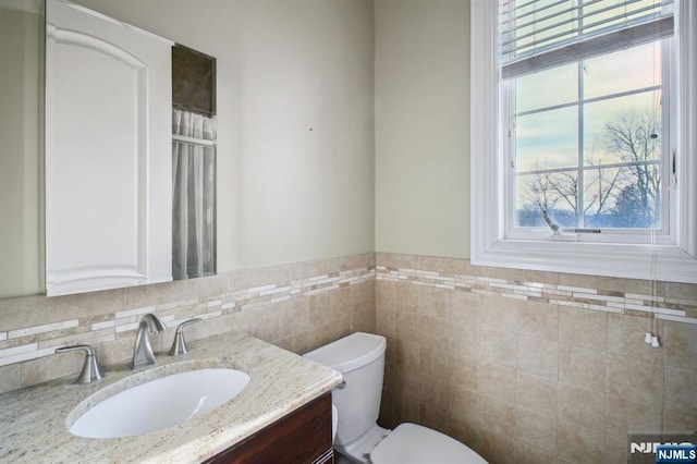 bathroom with vanity, tile walls, and toilet