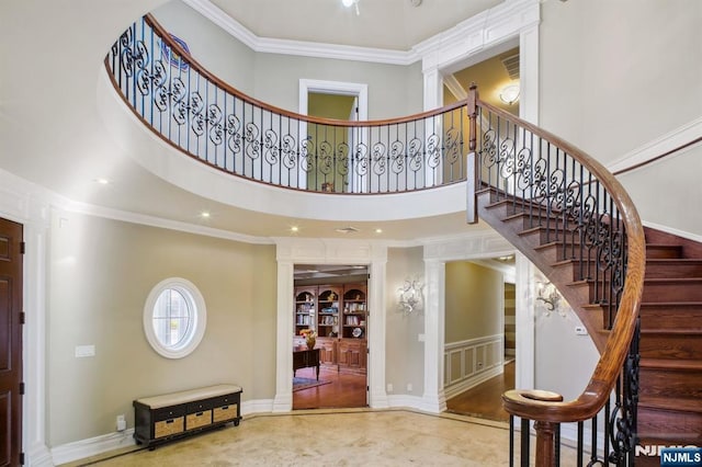 foyer featuring ornate columns, crown molding, and a towering ceiling