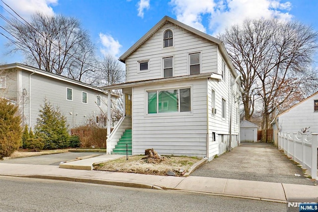 view of front of home with stairway, an outdoor structure, driveway, and fence