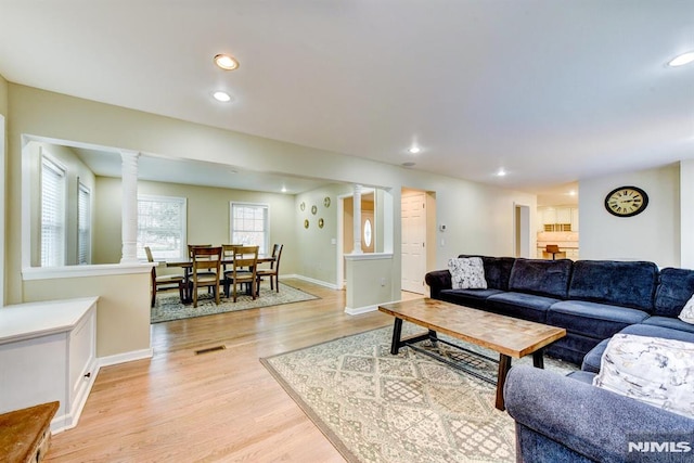 living room with decorative columns and light wood-type flooring