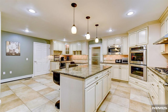 kitchen featuring a center island, decorative light fixtures, stainless steel appliances, tasteful backsplash, and stone counters