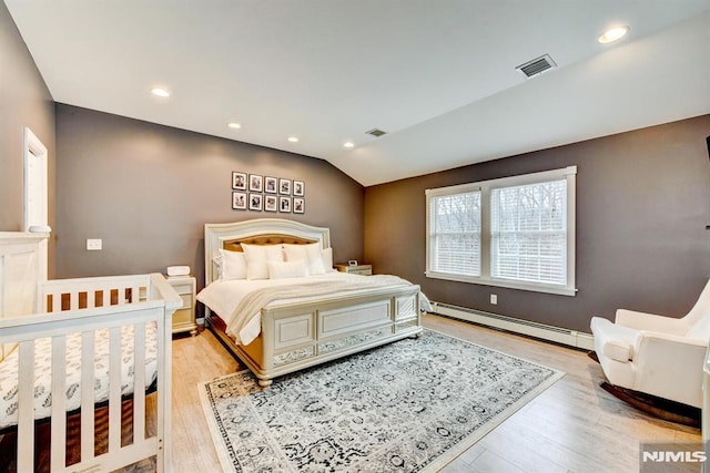 bedroom with a baseboard heating unit, lofted ceiling, and light hardwood / wood-style flooring