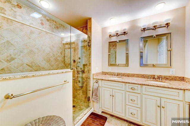 bathroom featuring a shower with shower door and vanity