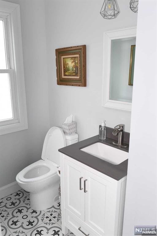 bathroom featuring toilet, vanity, tile patterned flooring, and a wealth of natural light