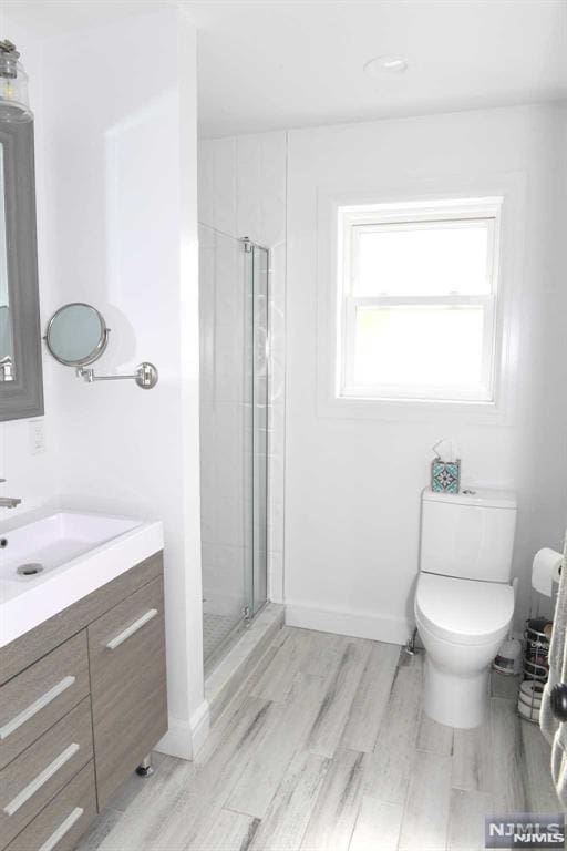 bathroom featuring hardwood / wood-style flooring, toilet, a shower with door, and vanity