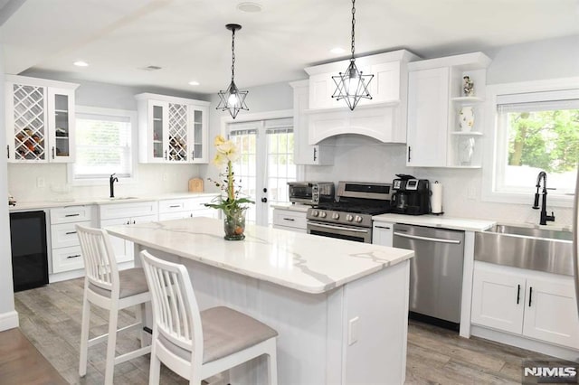 kitchen featuring stainless steel appliances, pendant lighting, white cabinets, and a center island