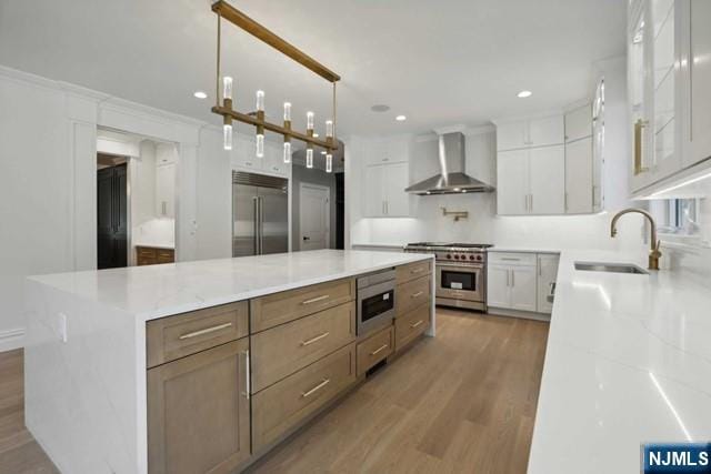 kitchen featuring sink, white cabinetry, a spacious island, high end appliances, and wall chimney exhaust hood