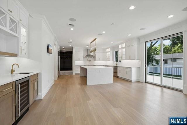 kitchen featuring white cabinetry, a center island, pendant lighting, and beverage cooler