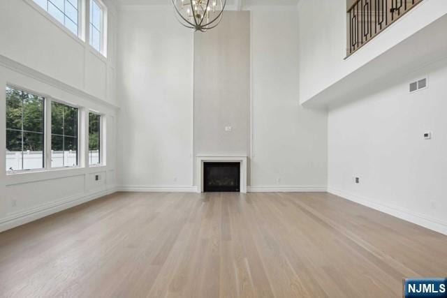 unfurnished living room with a high ceiling, hardwood / wood-style floors, and a notable chandelier