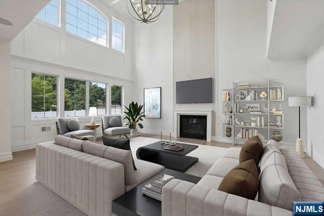 living room with a notable chandelier, a towering ceiling, and light wood-type flooring