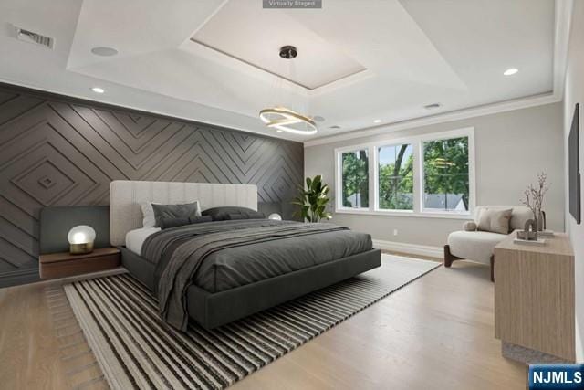 bedroom with a raised ceiling, ornamental molding, and light wood-type flooring