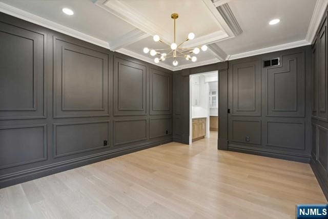 empty room with ornamental molding, light hardwood / wood-style floors, and a chandelier