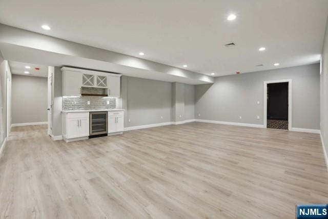 interior space featuring indoor bar, beverage cooler, and light hardwood / wood-style floors