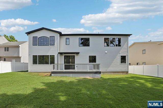 rear view of property with a deck and a lawn