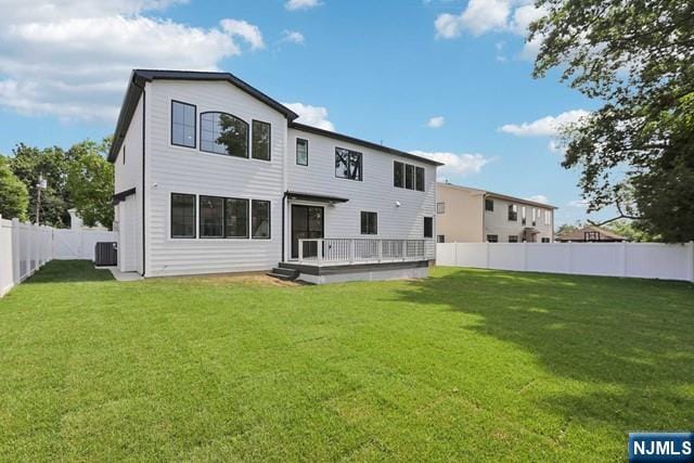 back of house with central AC unit and a yard