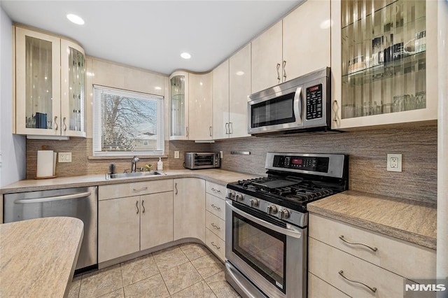 kitchen with sink, backsplash, light tile patterned floors, and stainless steel appliances