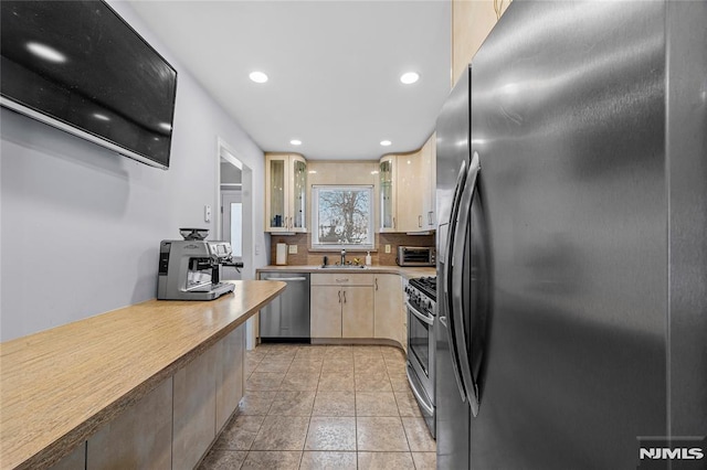 kitchen with sink, light tile patterned flooring, tasteful backsplash, and stainless steel appliances