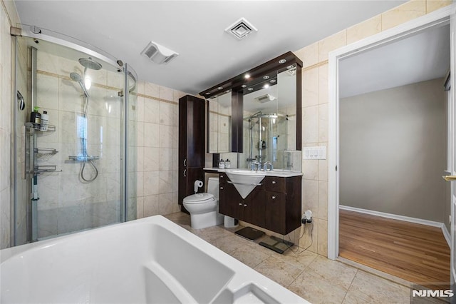 full bathroom featuring tile walls, toilet, vanity, and shower with separate bathtub