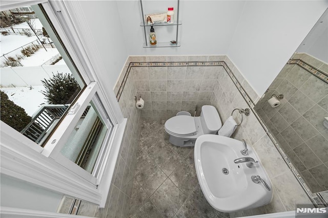 bathroom with sink, toilet, tile walls, and tile patterned floors