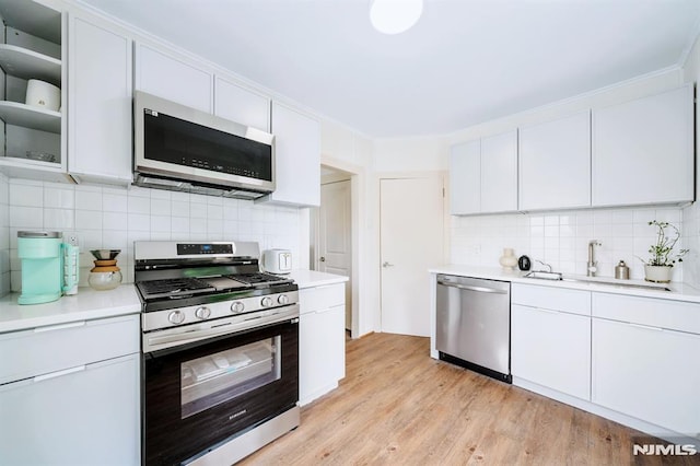 kitchen with sink, white cabinets, decorative backsplash, and stainless steel appliances