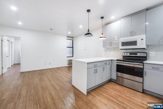 kitchen featuring gray cabinetry, hanging light fixtures, light hardwood / wood-style floors, kitchen peninsula, and electric stove