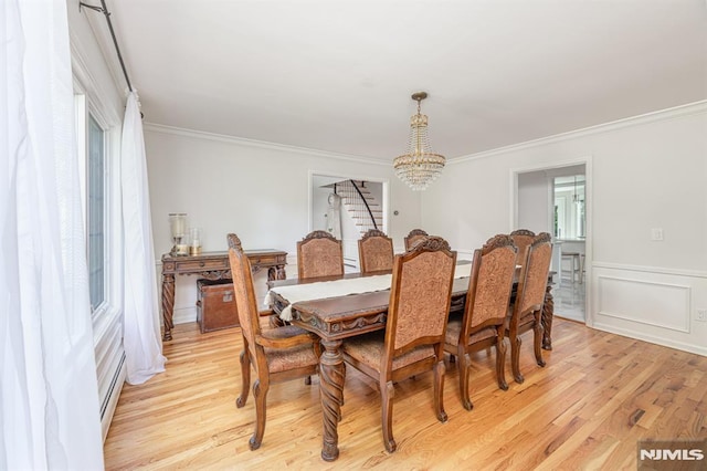 dining area with light wood-type flooring, a healthy amount of sunlight, a notable chandelier, and ornamental molding