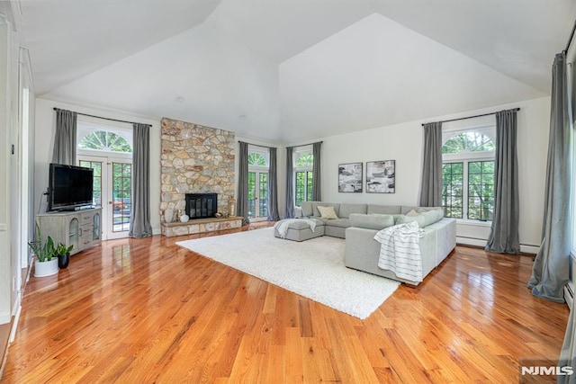 living room featuring light hardwood / wood-style flooring, lofted ceiling, and a stone fireplace