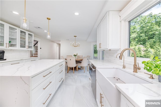 kitchen with backsplash, white cabinetry, hanging light fixtures, and a kitchen island